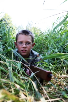 Picture of a boy in woods or small bushes representing a photo of teaching your child airsoft safety.