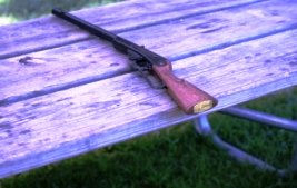 Photo of a bb gun wooden and black lying on a wood table