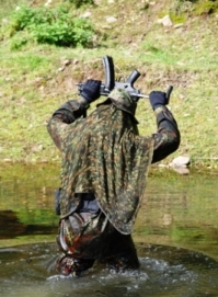 This photo represents the honor code in airsoft games, man dressed in camouflage wear with gun over his head in a surrendering manner